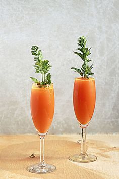 two glasses filled with orange juice and garnished with greenery