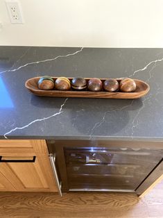 a wooden tray filled with donuts on top of a kitchen counter