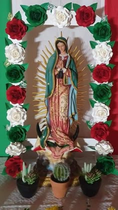 a statue of the virgin mary surrounded by flowers and succulents on a table