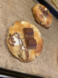 two chocolate chip cookies sitting on top of a cookie sheet