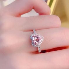 a woman's hand holding a pink diamond ring