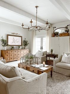 a living room filled with furniture and a chandelier hanging over the top of it