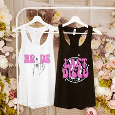 two women's tank tops are hanging on a rack with flowers in the background