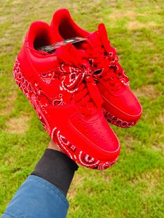 someone is holding up their red nike air force sneakers with bandana print on them