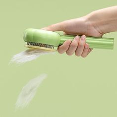 a hand holding a green brush with white feathers coming out of it's handle