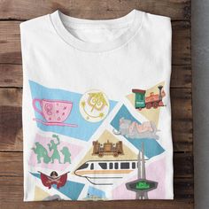 a white t - shirt with colorful pictures on it sitting on top of a wooden table