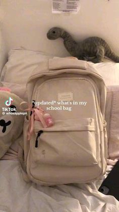 two stuffed animals sitting on top of a bed next to a backpack and teddy bear