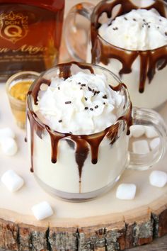 two mugs filled with hot chocolate and marshmallows on a white plate