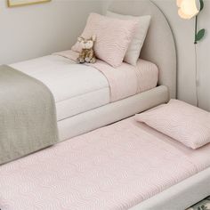 a bed with two pillows and a teddy bear sitting on top of the mattresses