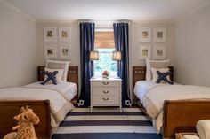 two twin beds in a bedroom with blue drapes and striped rug on the floor