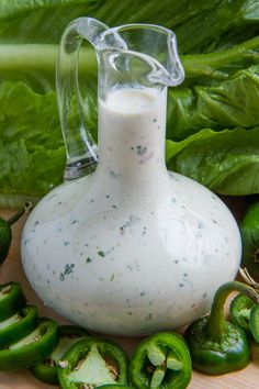 green peppers surrounding a jug of dressing on a cutting board