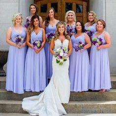 a group of women standing next to each other in front of a building holding bouquets