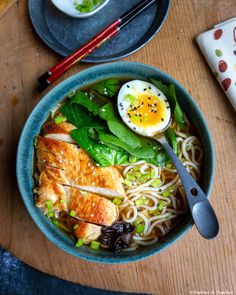 a bowl filled with noodles, meat and veggies next to chopsticks