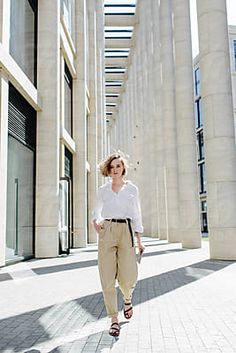 a woman in white shirt and tan pants walking down street