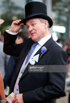 a man in a top hat and suit is holding his hand to his head as he stands