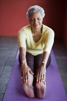 an older woman is sitting on a yoga mat