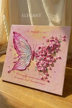 a greeting card with pink flowers and a butterfly on the front, sitting on a table