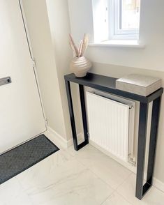 a black and white console table with a vase on it in front of a door