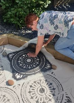 a woman laying on top of a table covered in black and white designs next to rocks