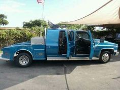 a blue pick up truck with the door open and an american flag in the back