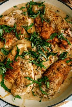 a pan filled with chicken covered in gravy and garnished with green leaves