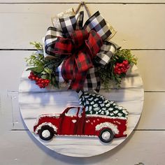 a red truck with a christmas tree on it is hanging on a white wooden wall