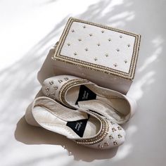 a pair of white ballet shoes sitting in front of a box with pearls on it