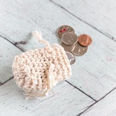 a crocheted coin purse sitting on top of a wooden floor next to coins