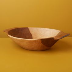 a wooden bowl sitting on top of a yellow table