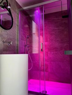 a bathroom with a purple light on the wall and a shower in the corner next to it