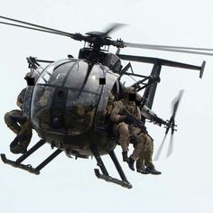 soldiers climbing into the back of a helicopter in mid air while another man is on the ground