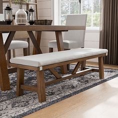 a dining room table with two chairs and a bench in front of it on a rug