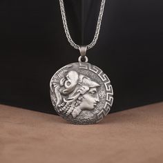 a silver necklace with an image of a woman's face on the front and side