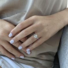 a woman's hands with white manicures and a ring on her finger