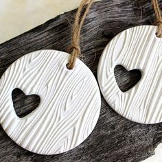 two wooden ornaments with hearts hanging from strings