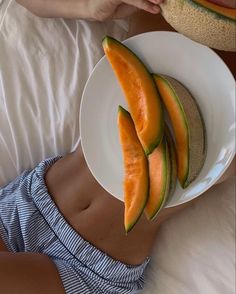 a person holding a plate with melon slices on it