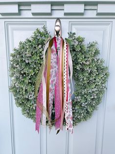 a wreath with ribbons hanging from it's side on a door handle, in front of a white door