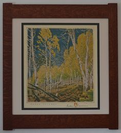 a painting hanging on the wall in front of a wooden frame with trees and leaves