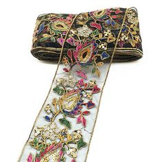 a black purse with colorful flowers on it and a white ribbon hanging from the side