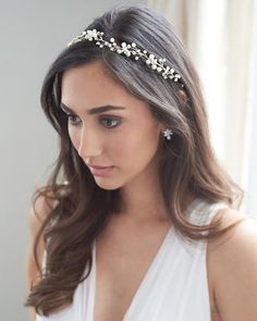 a woman wearing a white dress and a gold headpiece with flowers on it's side