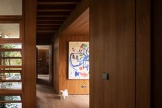 a dog is standing in the hallway between two wooden walls and a painting on the wall