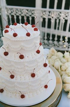 a white wedding cake with cherries on top