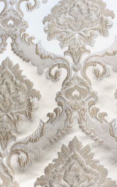 an intricately designed wallpaper with white and gold designs on the fabric, as well as