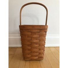 a brown basket sitting on top of a wooden floor next to a white wall and hardwood floors