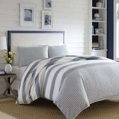 a bed with blue and white striped comforter in a room next to a window