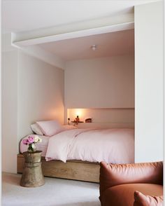 there is a bed with pink sheets and pillows in the room that looks like it has been made into a loft