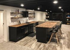 a kitchen with black cabinets and wooden counter tops next to a tv on the wall