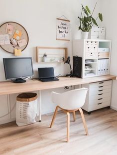 a desk with two laptops and a desktop computer on it in front of a clock