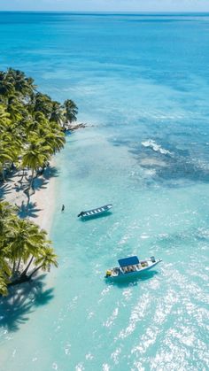 two boats are in the water near some palm trees and blue water with white sand