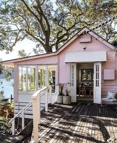 a pink house sitting on top of a wooden deck